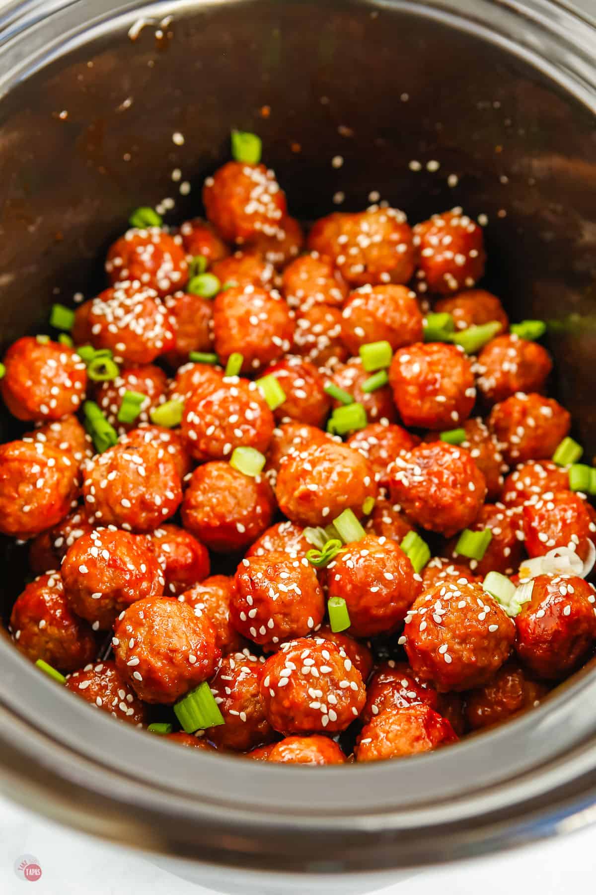 black pot with meatballs and sesame seeds in it