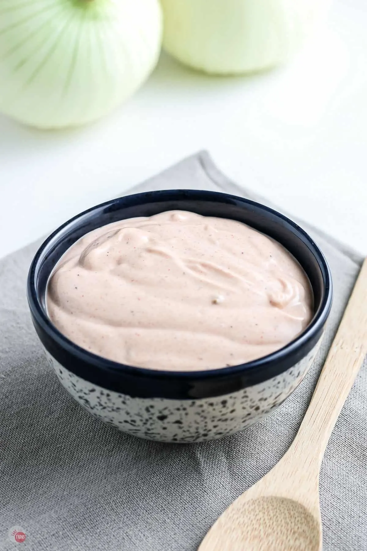 small blue bowl of pink dip on a grey napkin