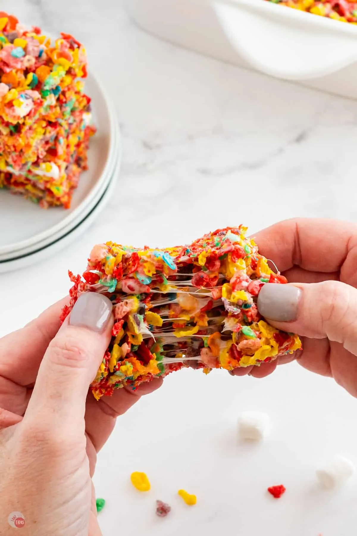 two hands pulling apart a fruity pebbles treat