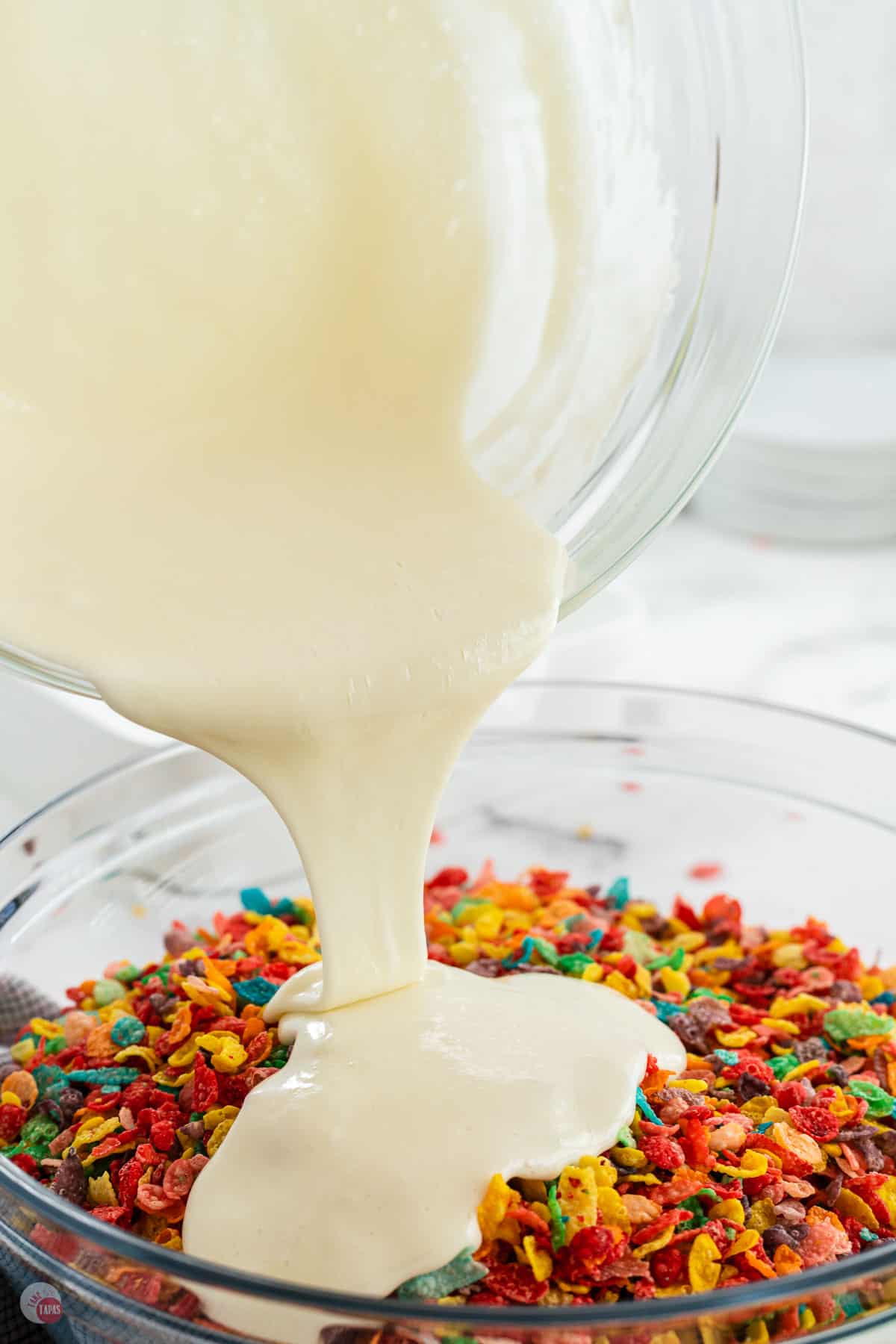marshmallow mix pouring over fruity pebbles cereal