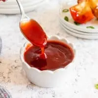 spoon of red sauce in a white bowl