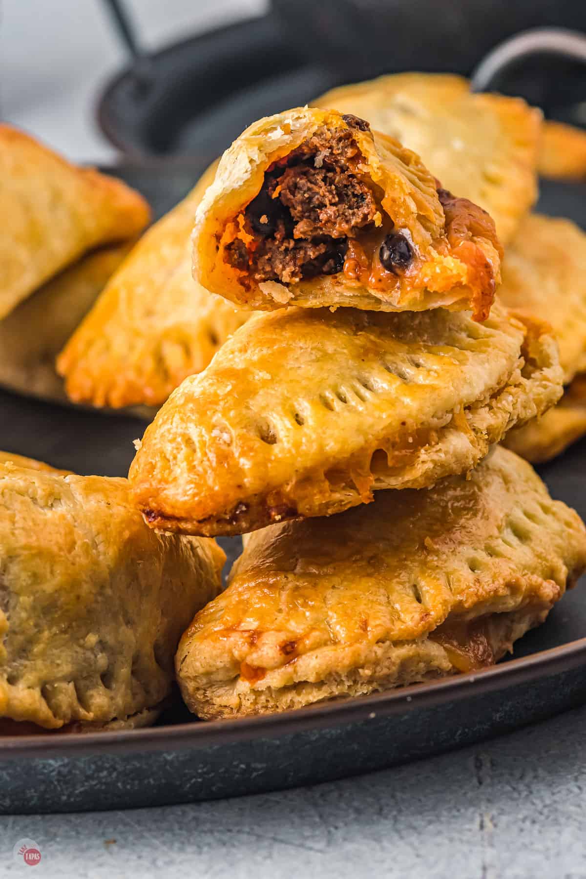 stack of taco empanadas on a black plate