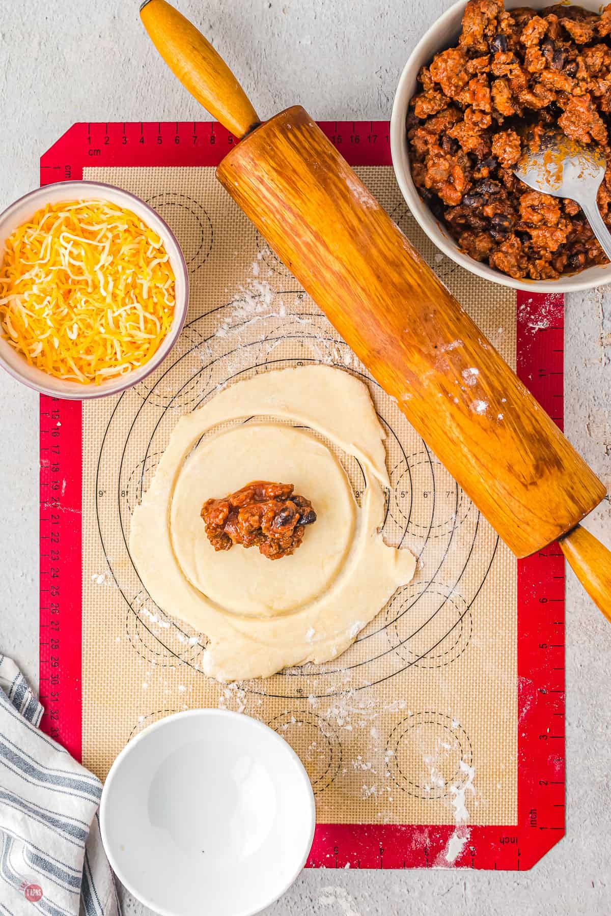 dough on a pastry board with taco meat