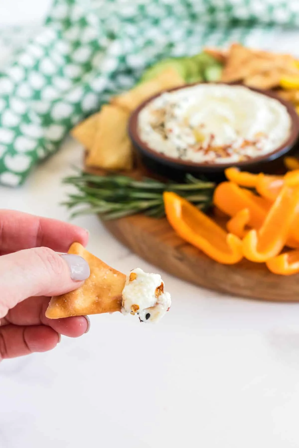 hand holding chip with feta dip on it