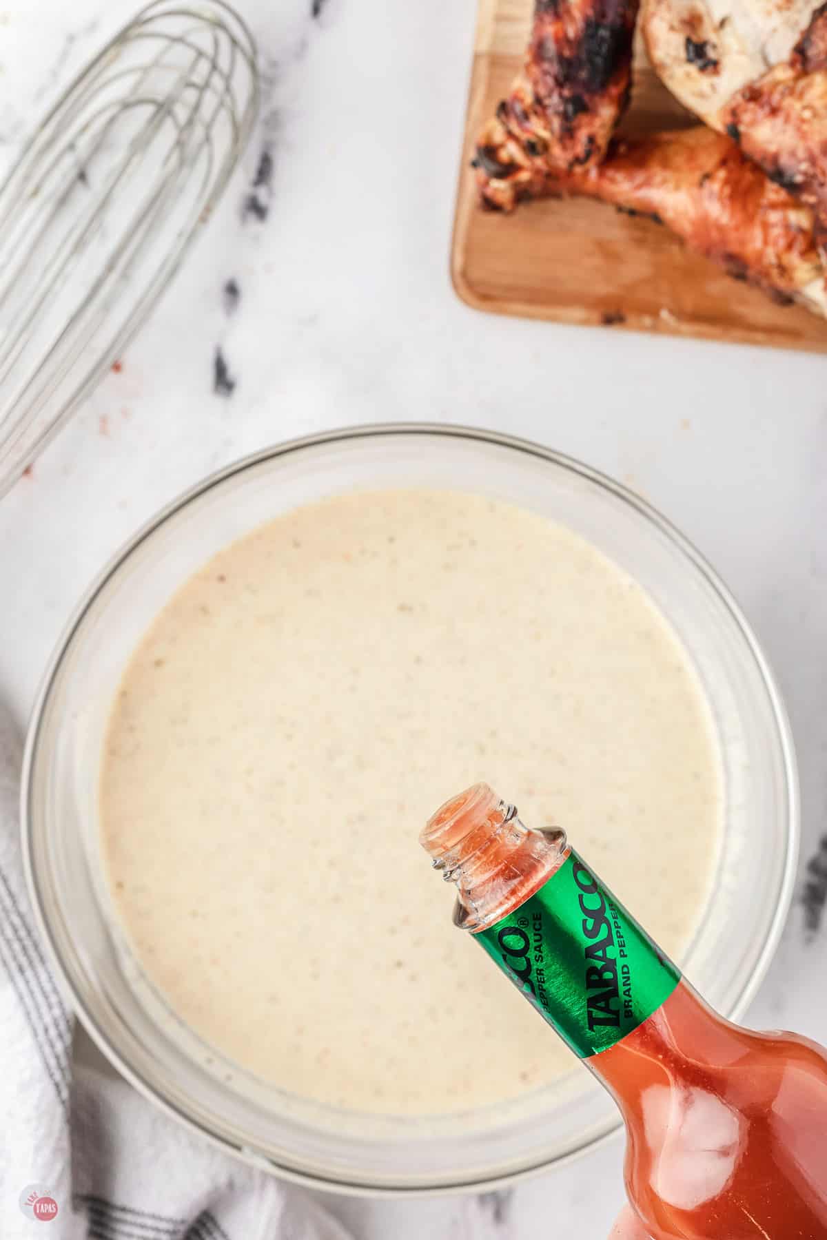 hot sauce bottle over a bowl of white sauce