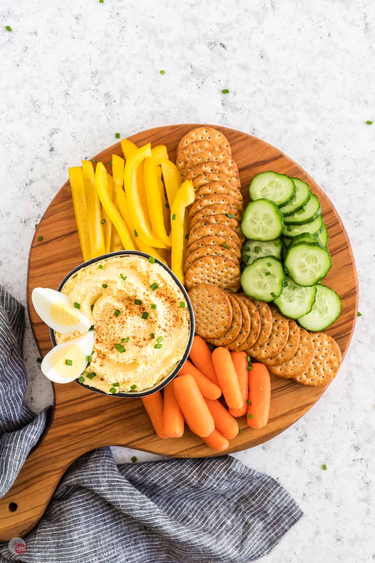 wood board with a bowl of dip and crackers