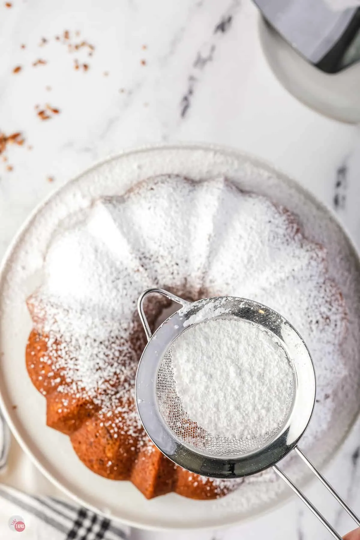 cake being dusted with powdered sugar