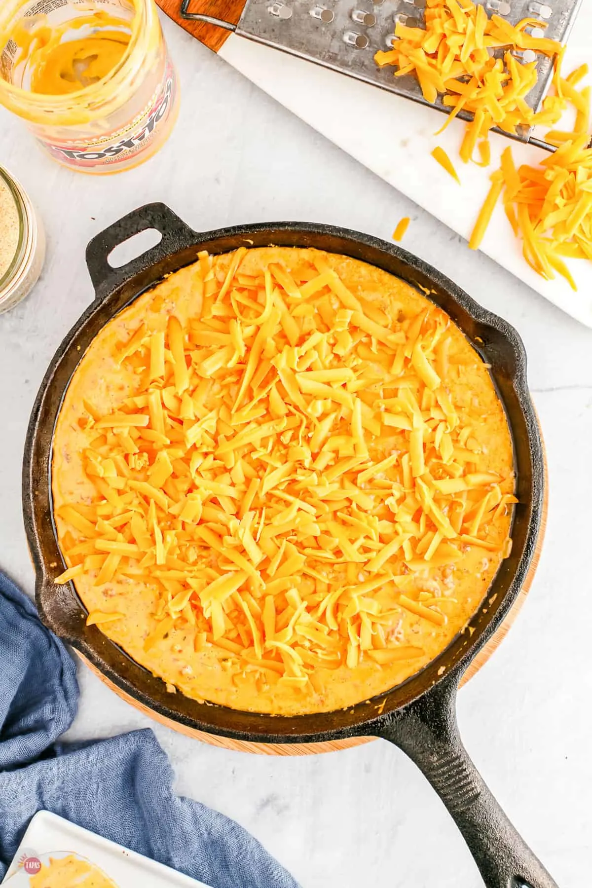 shredded cheese on dip in a skillet