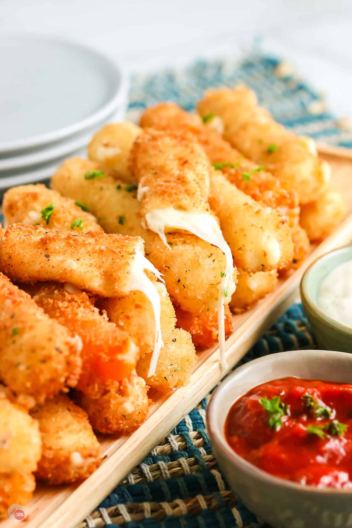 pile of cheese with one broken in half and a small bowl of red sauce