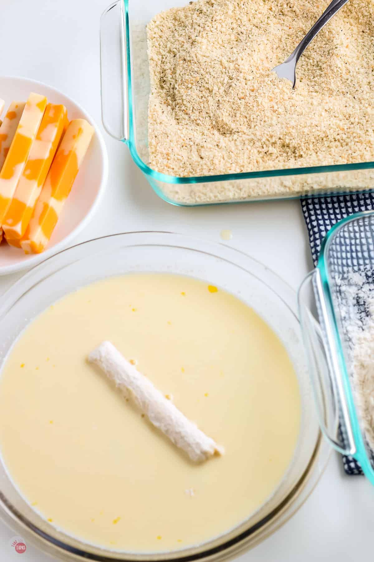 flour coated cheese stick in a bowl of milk