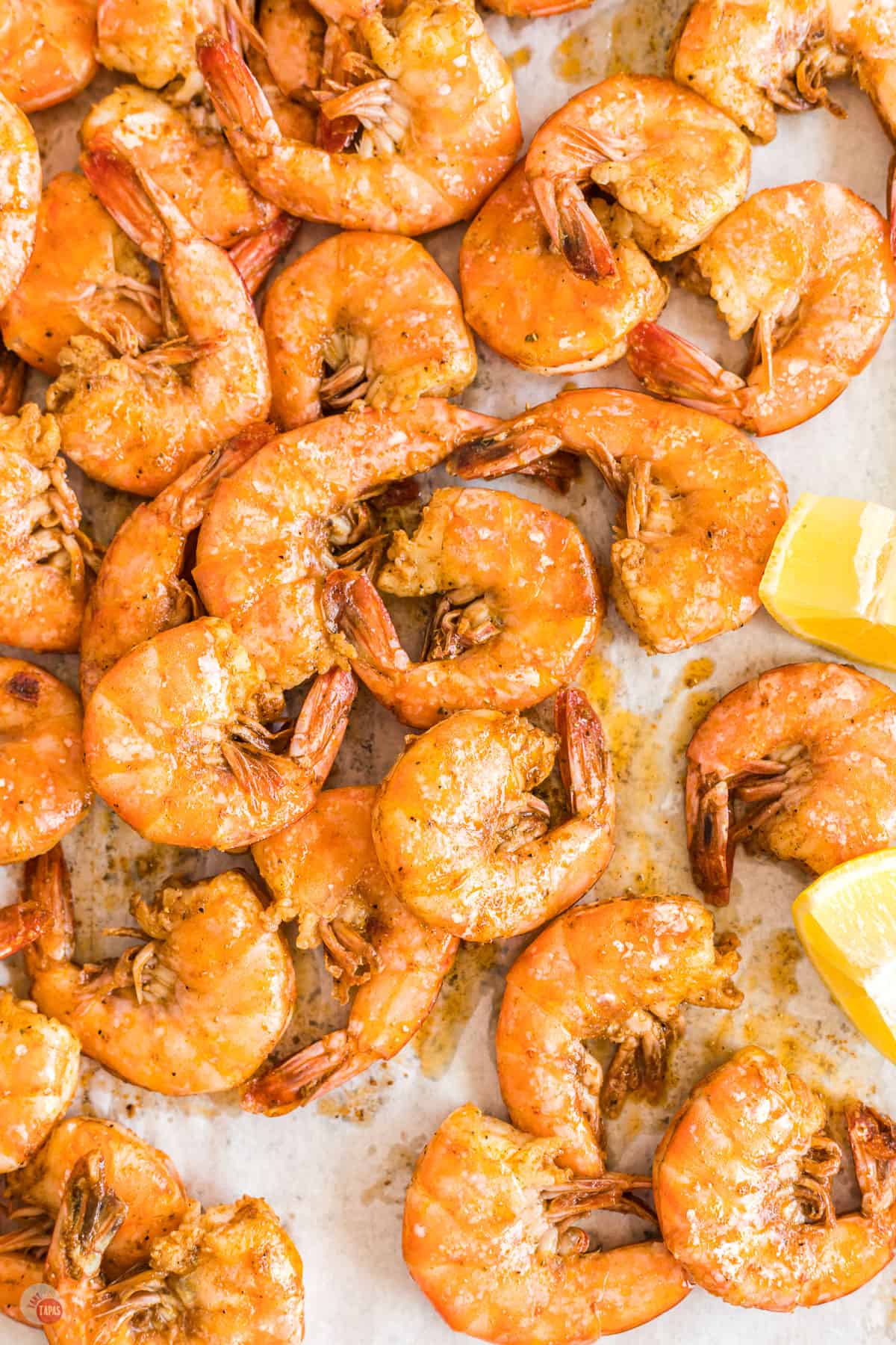 sheet pan with baked shrimp and lemon wedges