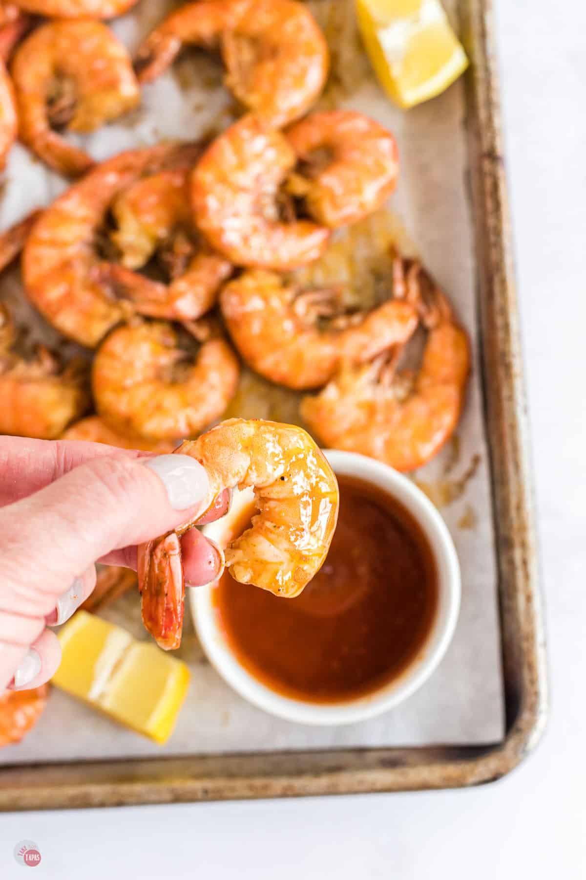 hand dipping shrimp in bowl