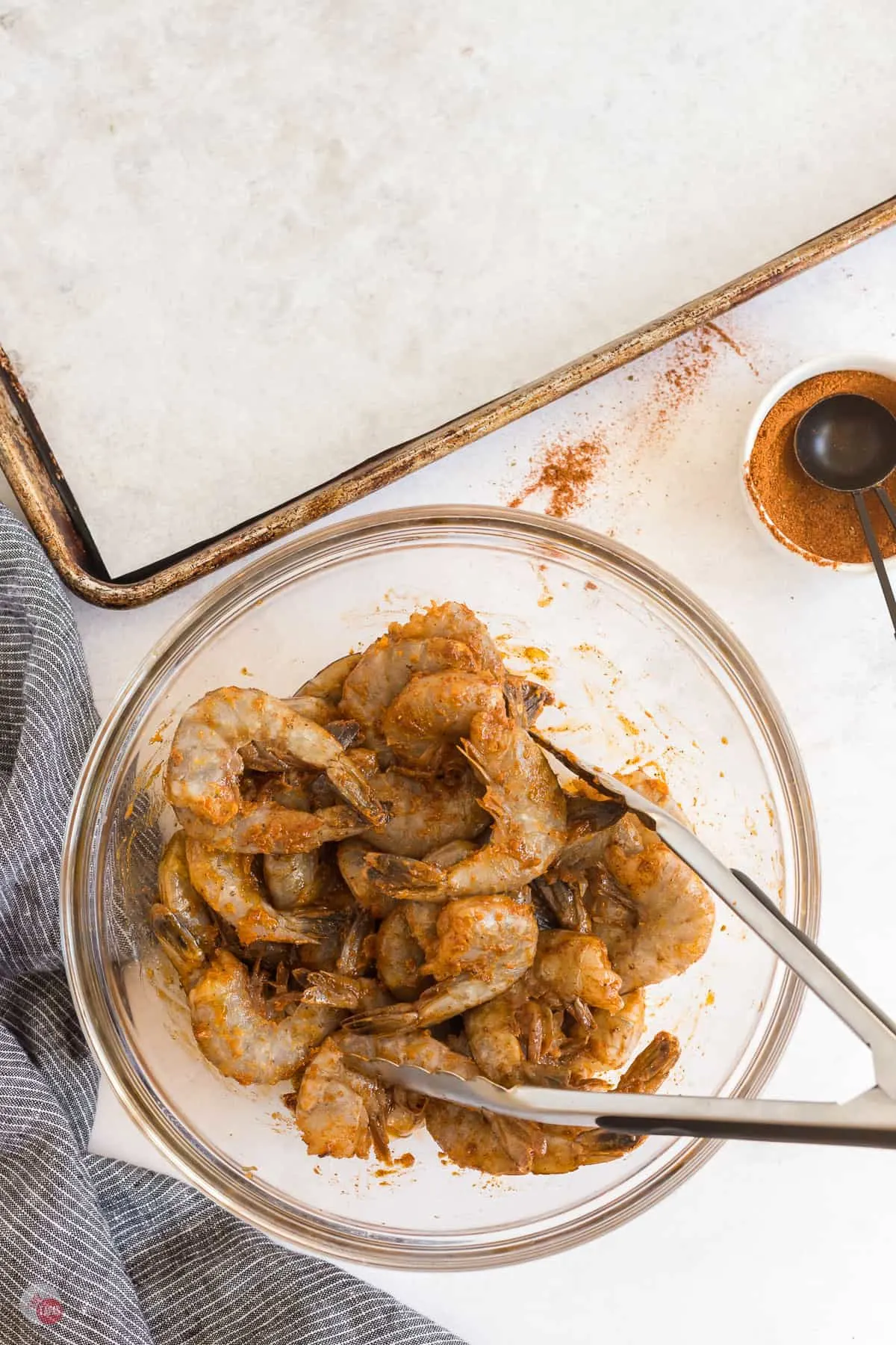 uncooked shrimp with tongs in a bowl