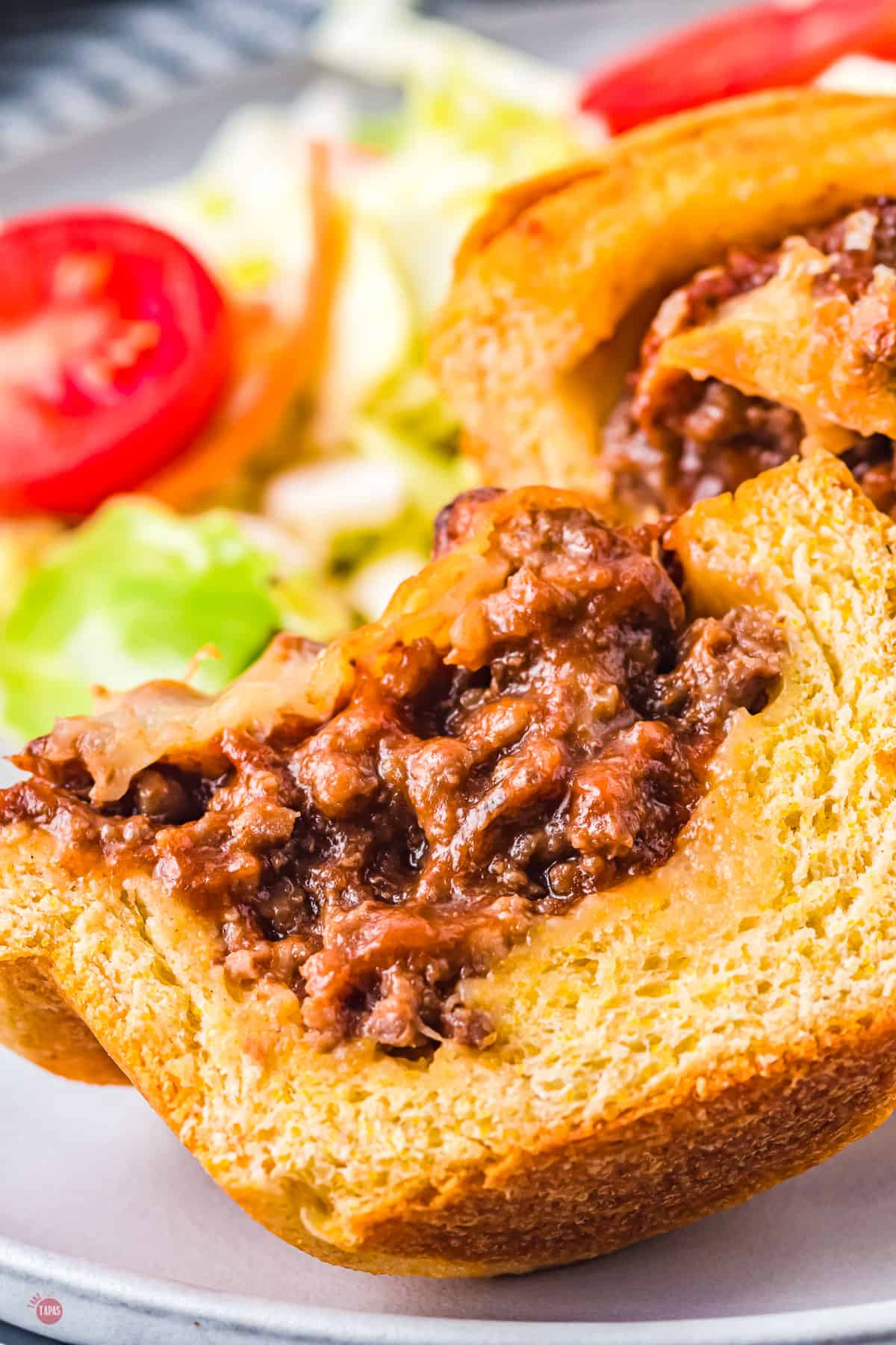 Close up of a sloppy joe cup on a plate with salad.