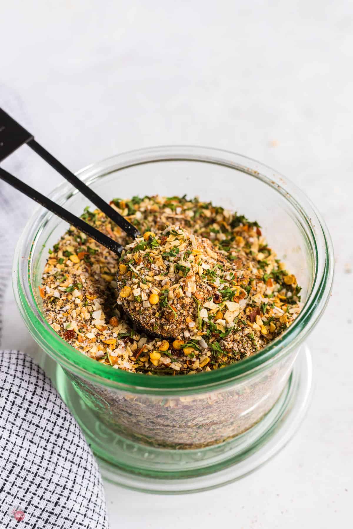 jar of seasoning blend with a black measuring spoon in it