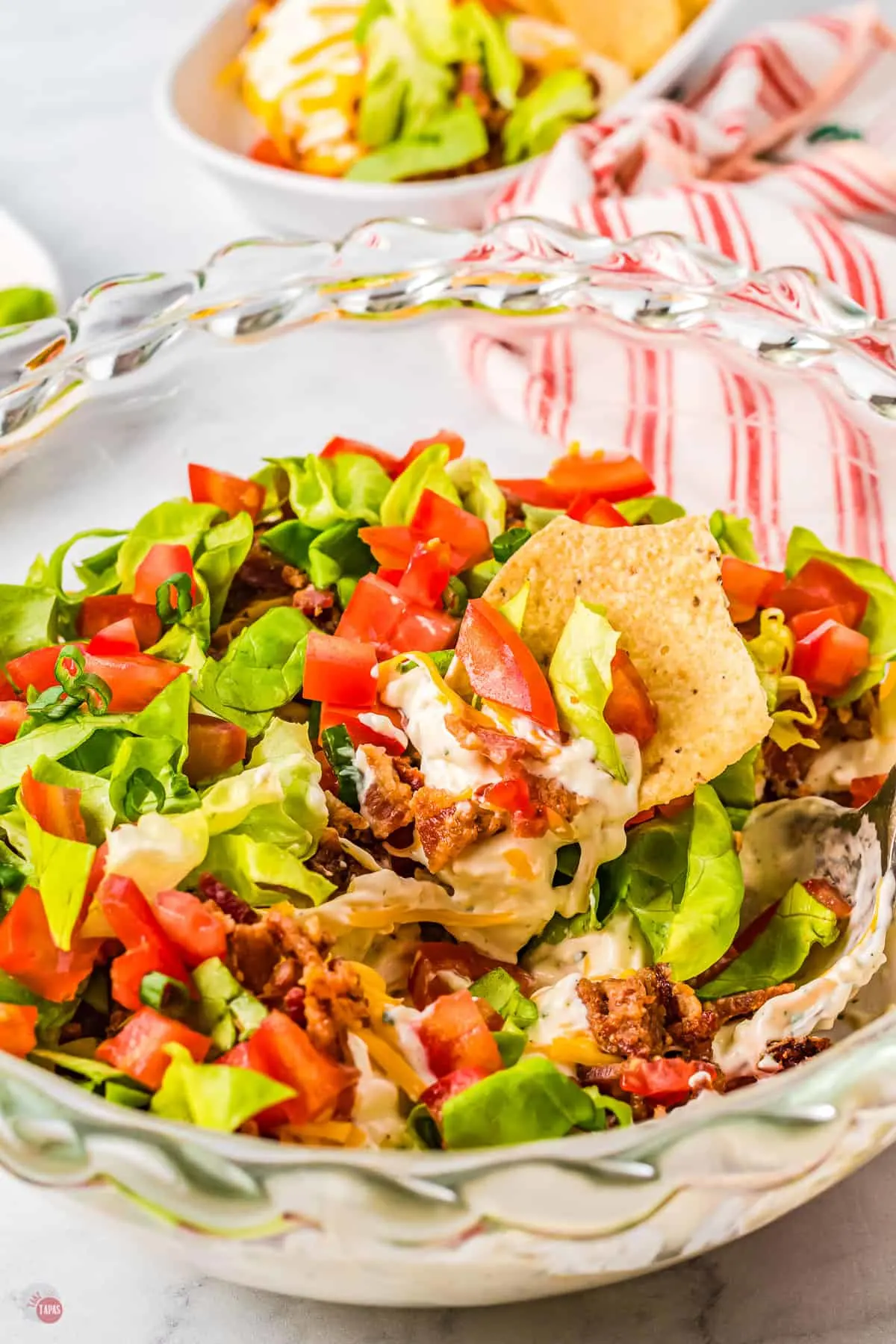 Glass bowl of BLT Dip with chips in it.