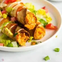 three buffalo chicken taquitos on a plate with lettuce