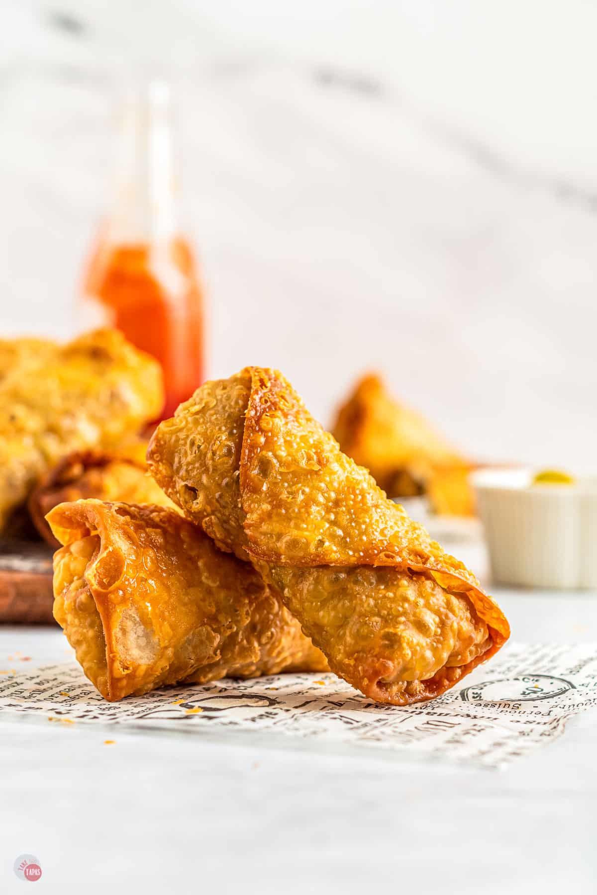 Crispy egg rolls on top of newspaper.
