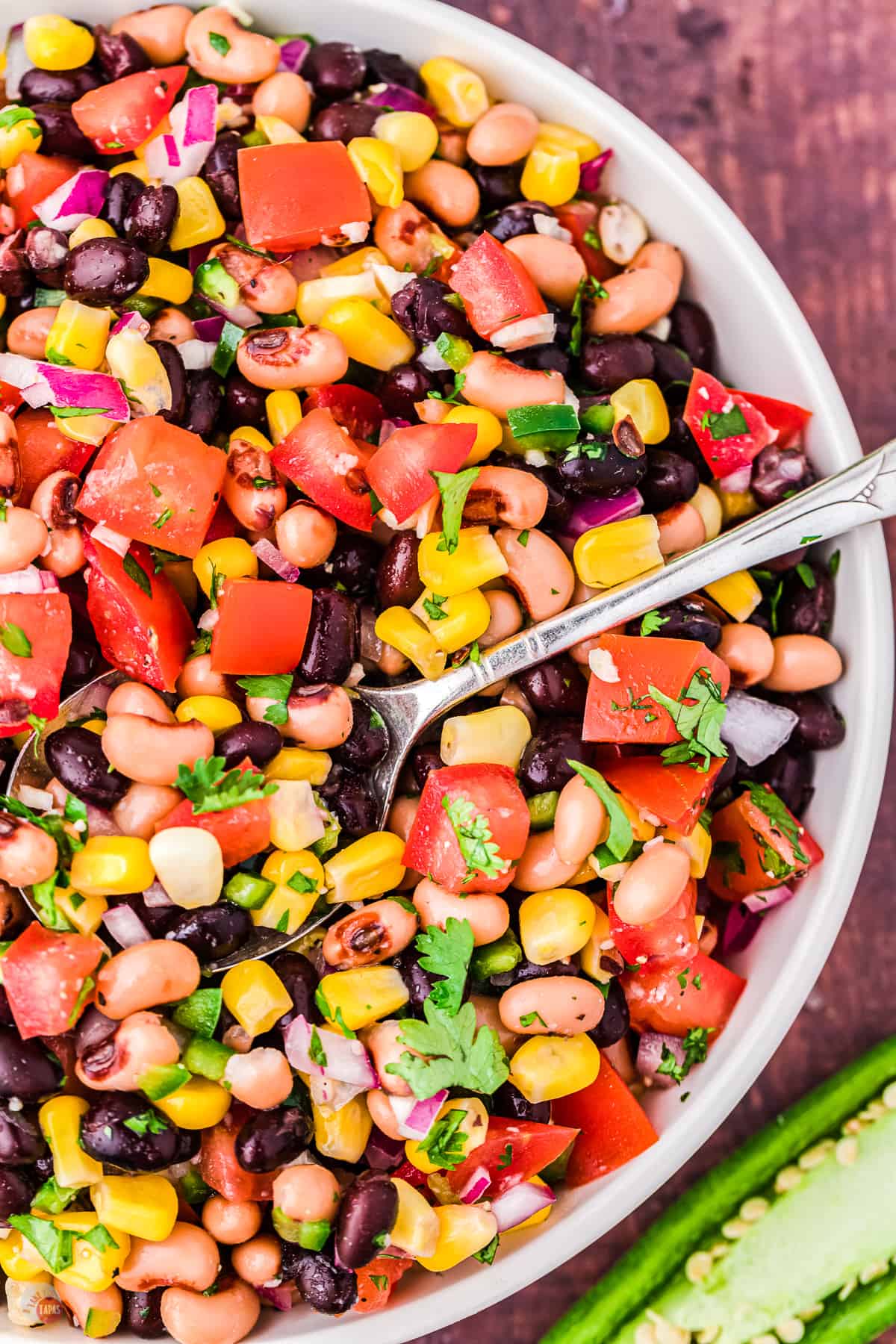 Close up of a white bowl filled with cowboy caviar dip with a spoon in it.