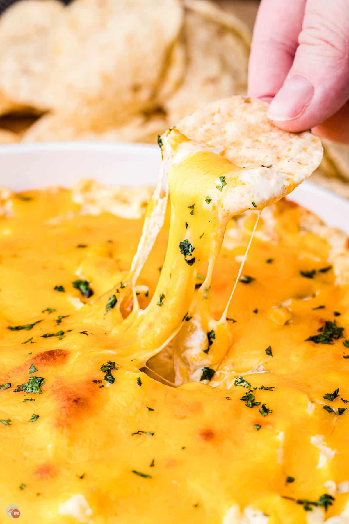 bowl of green chile dip with chip scooping some out