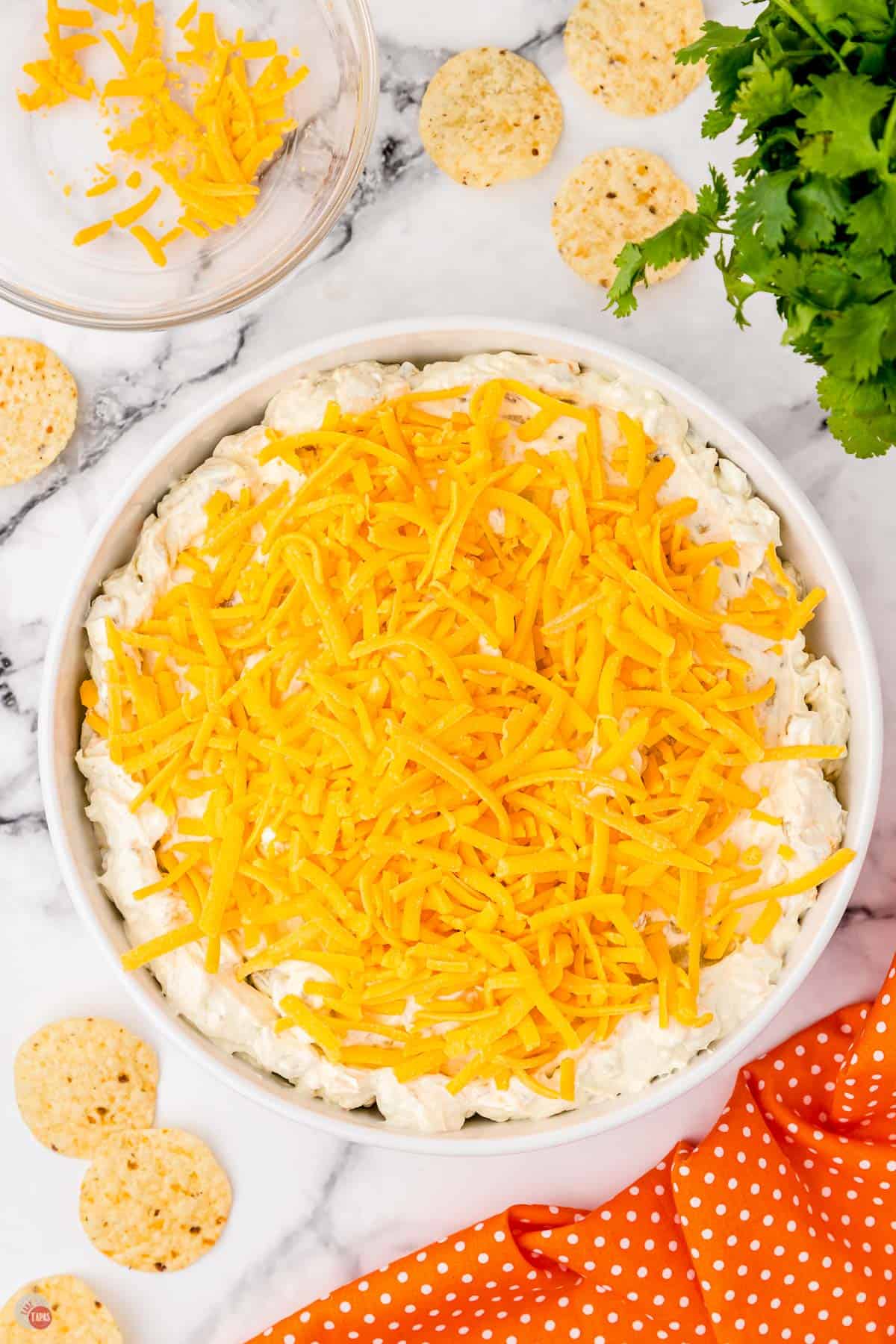 unbaked dip in a baking dish with shredded cheese on top