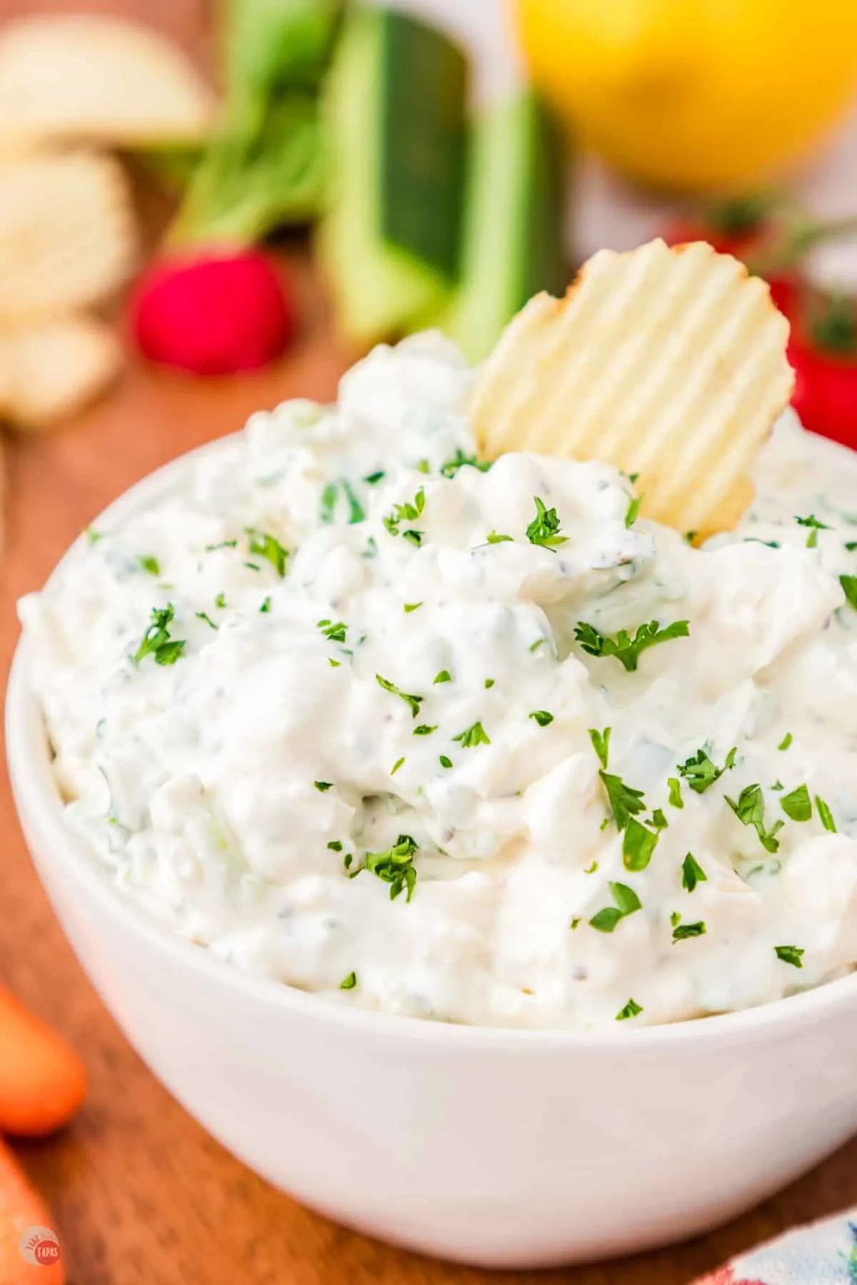 bowl of green onion sour cream dip with chip and topped with fresh chives