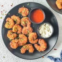 black plate with fried shrimp and two dipping sauces