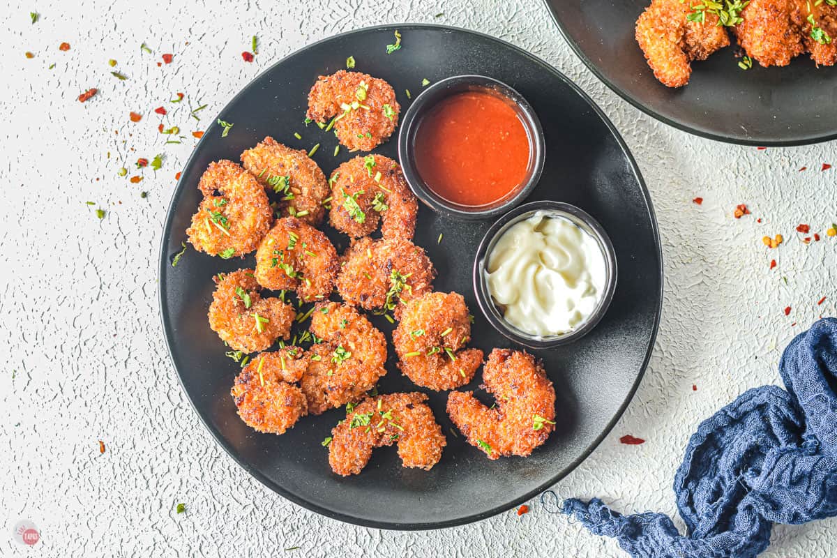 black plate with fried shrimp and two dipping sauces