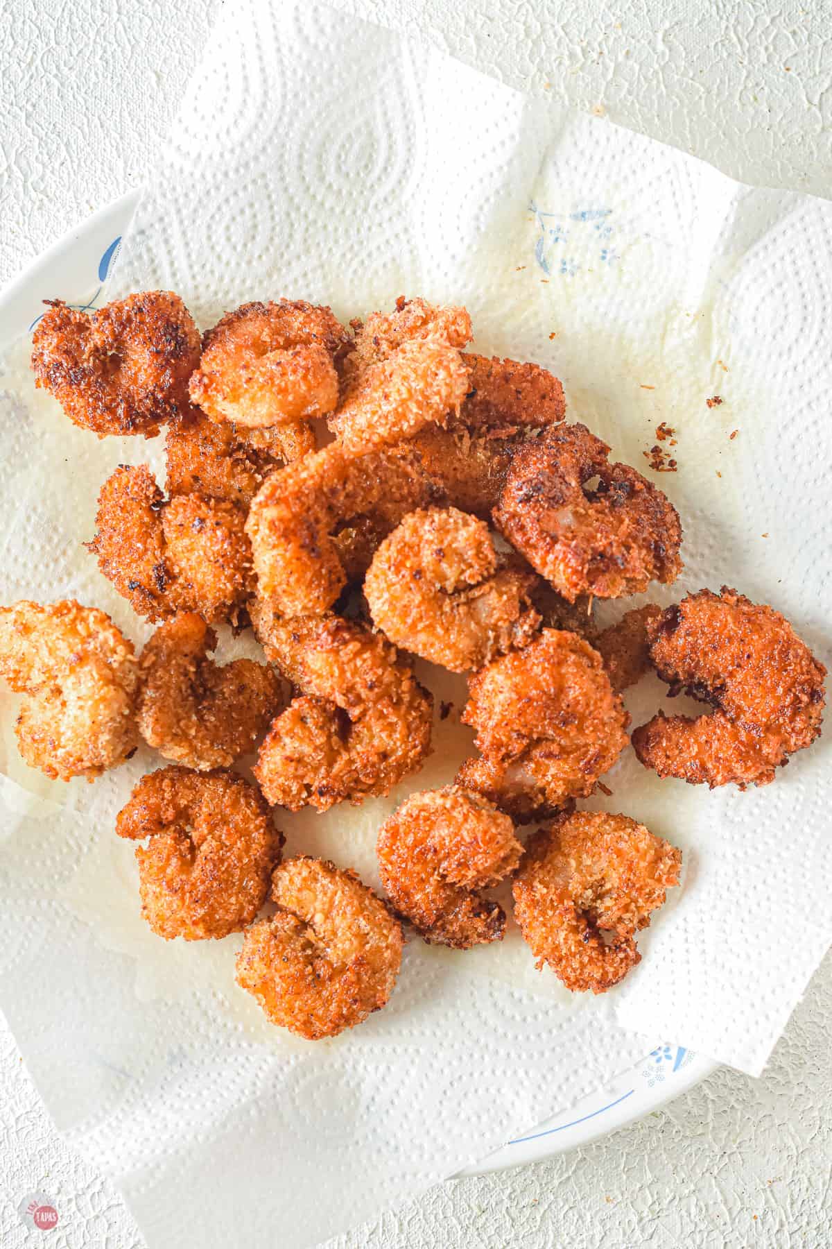 plate with paper towel and a pile of fried shrimp