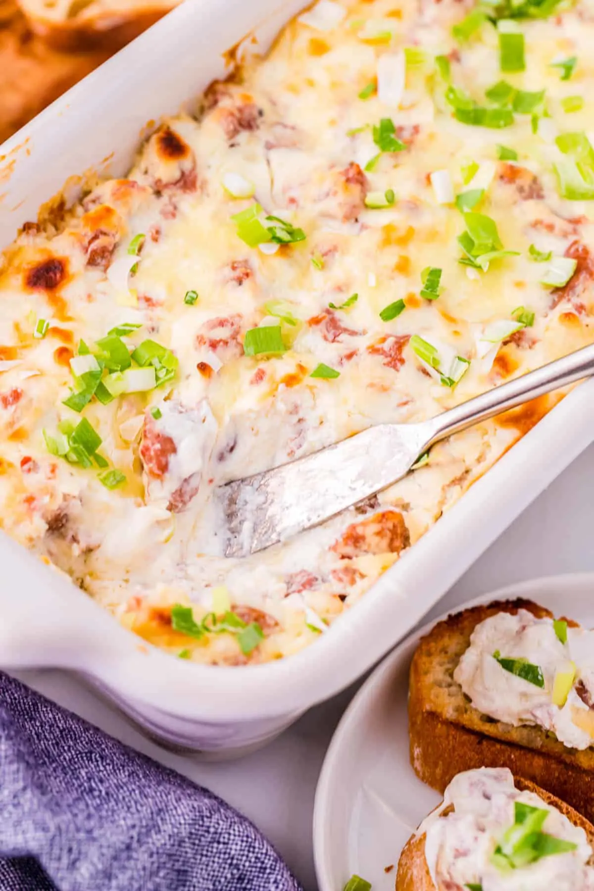 baking dish full of boudin dip with a scoop missing