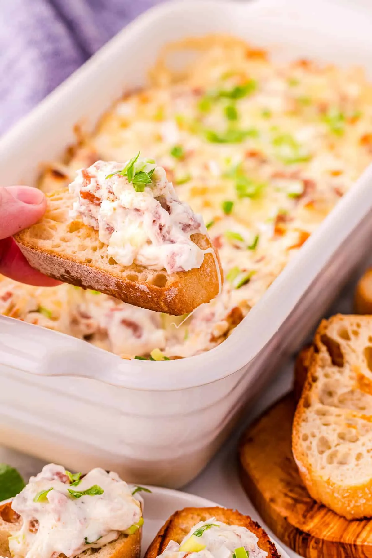 hand with crostini topped with dip