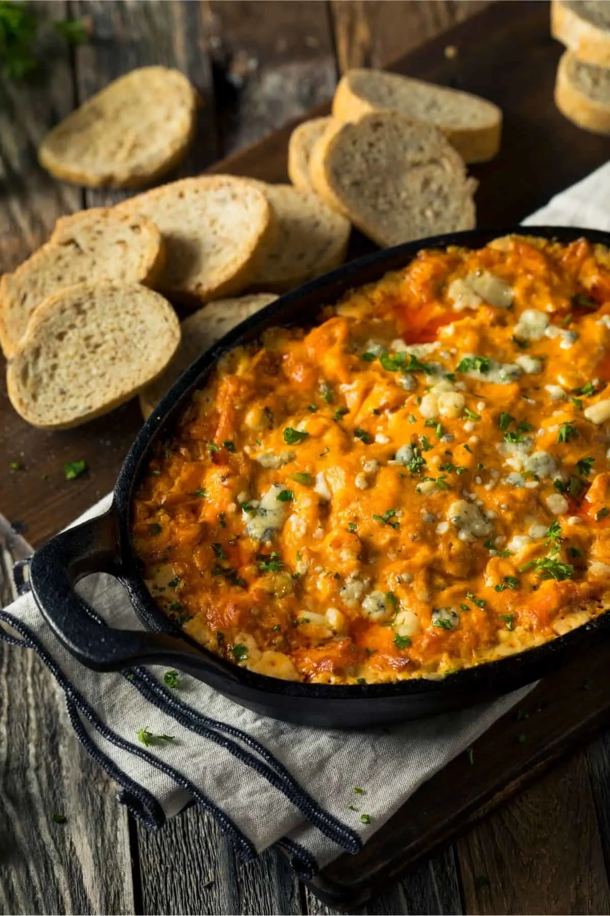 cast iron pan full of buffalo chicken dip beside slices of wheat bread