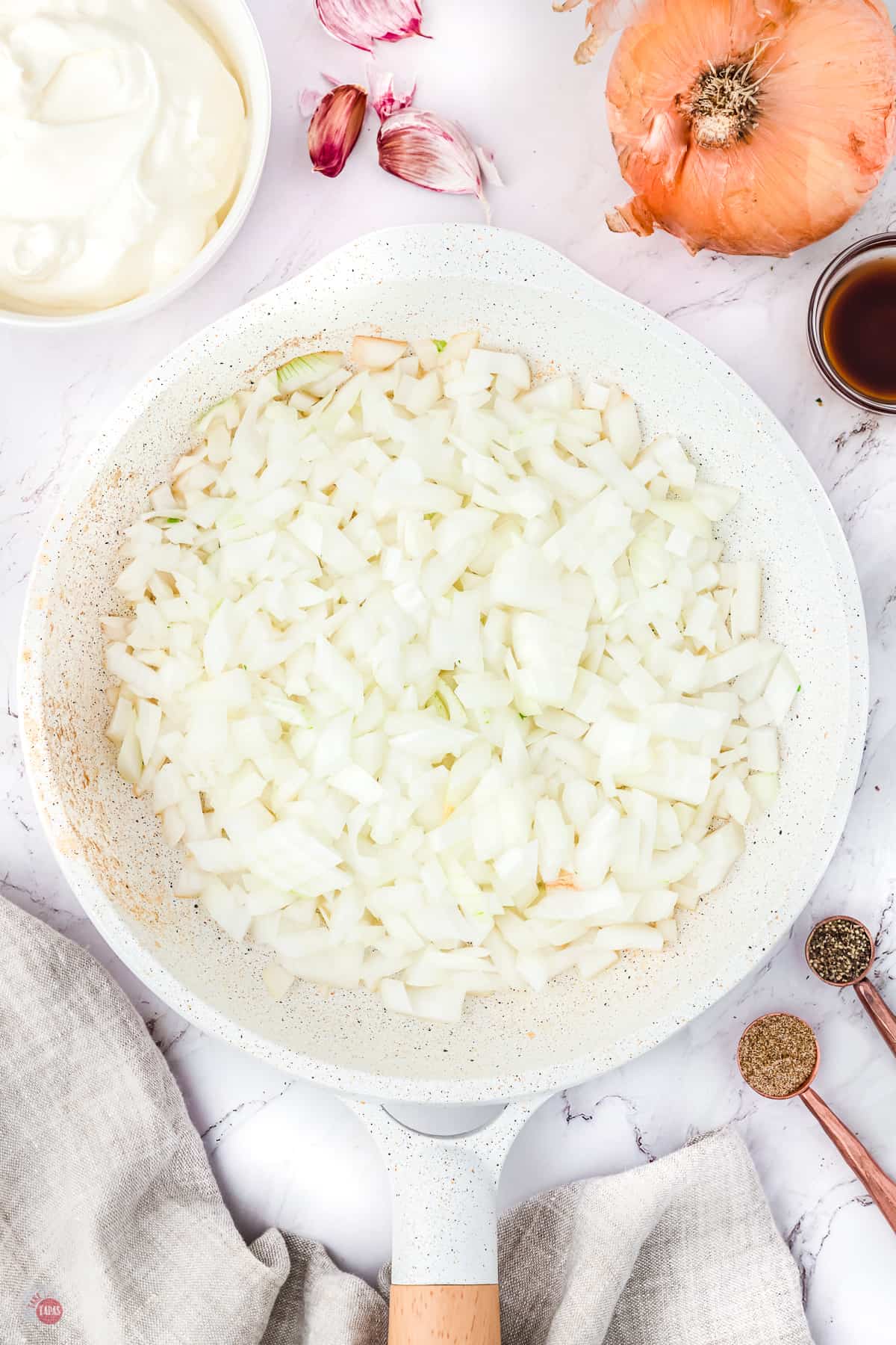 large sauté pan with raw onions in it