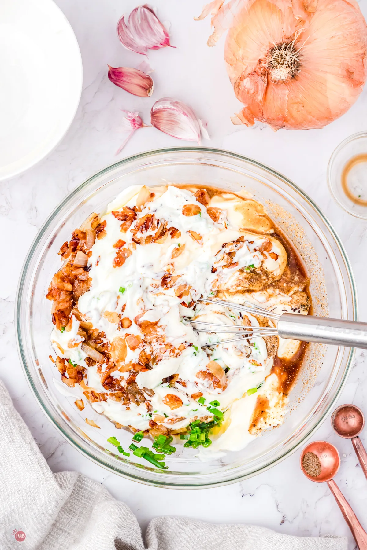 homemade version of french onion dip being combined in a mixing bowl 