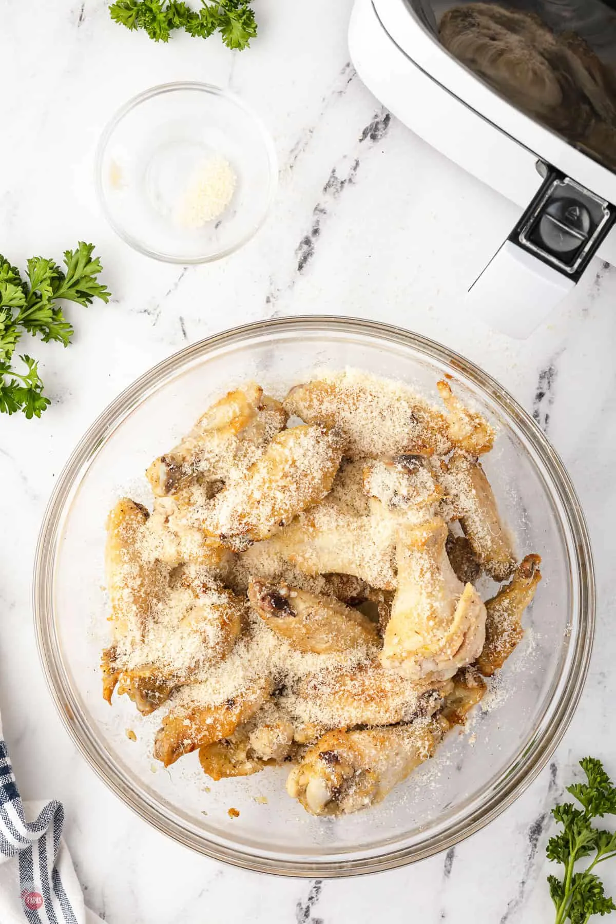 fried wings in a bowl with parmesan cheese sprinkled on