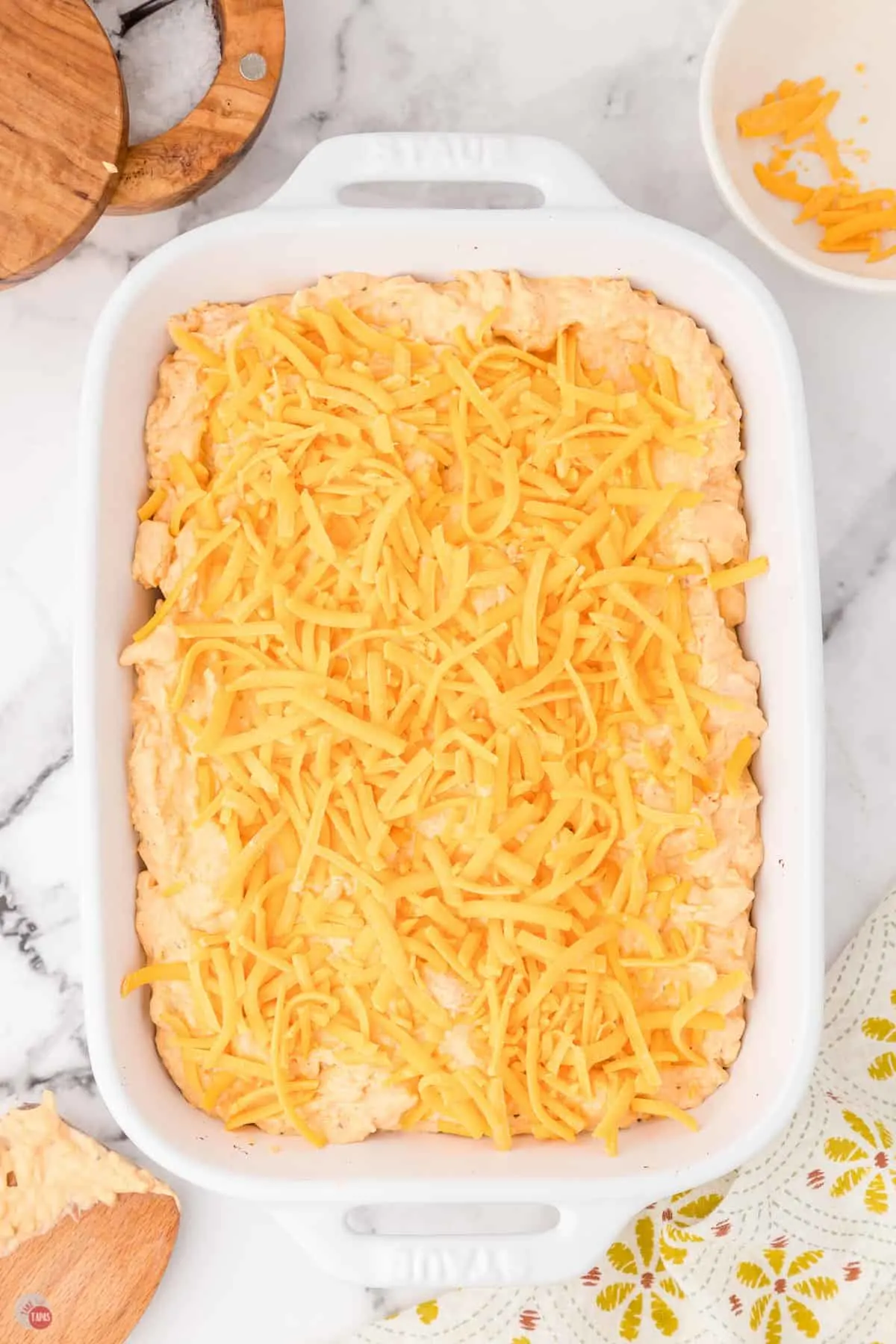 white casserole dish with shredded cheese on top