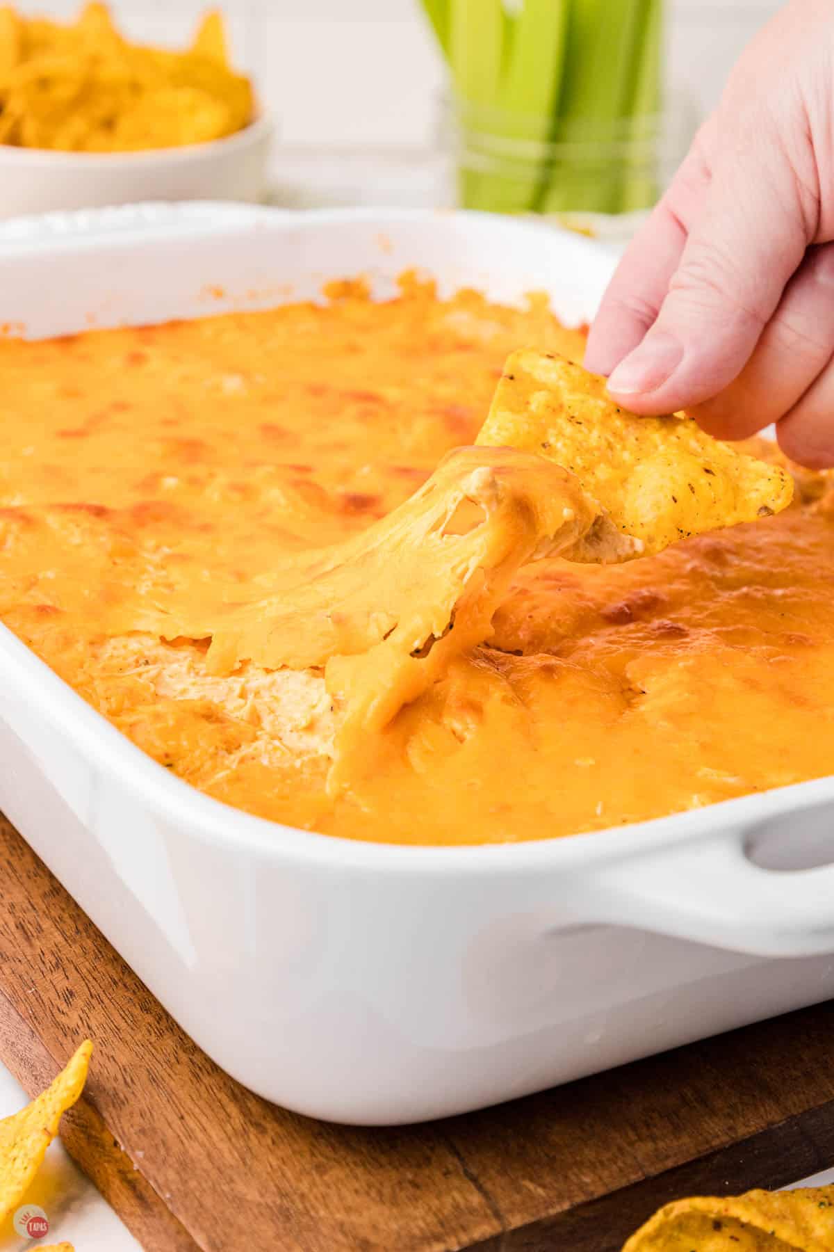 chip pulling dip out of a white bowl