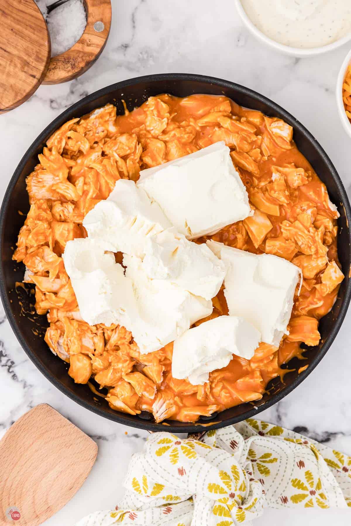 buffalo chicken in a skillet with cream cheese on top