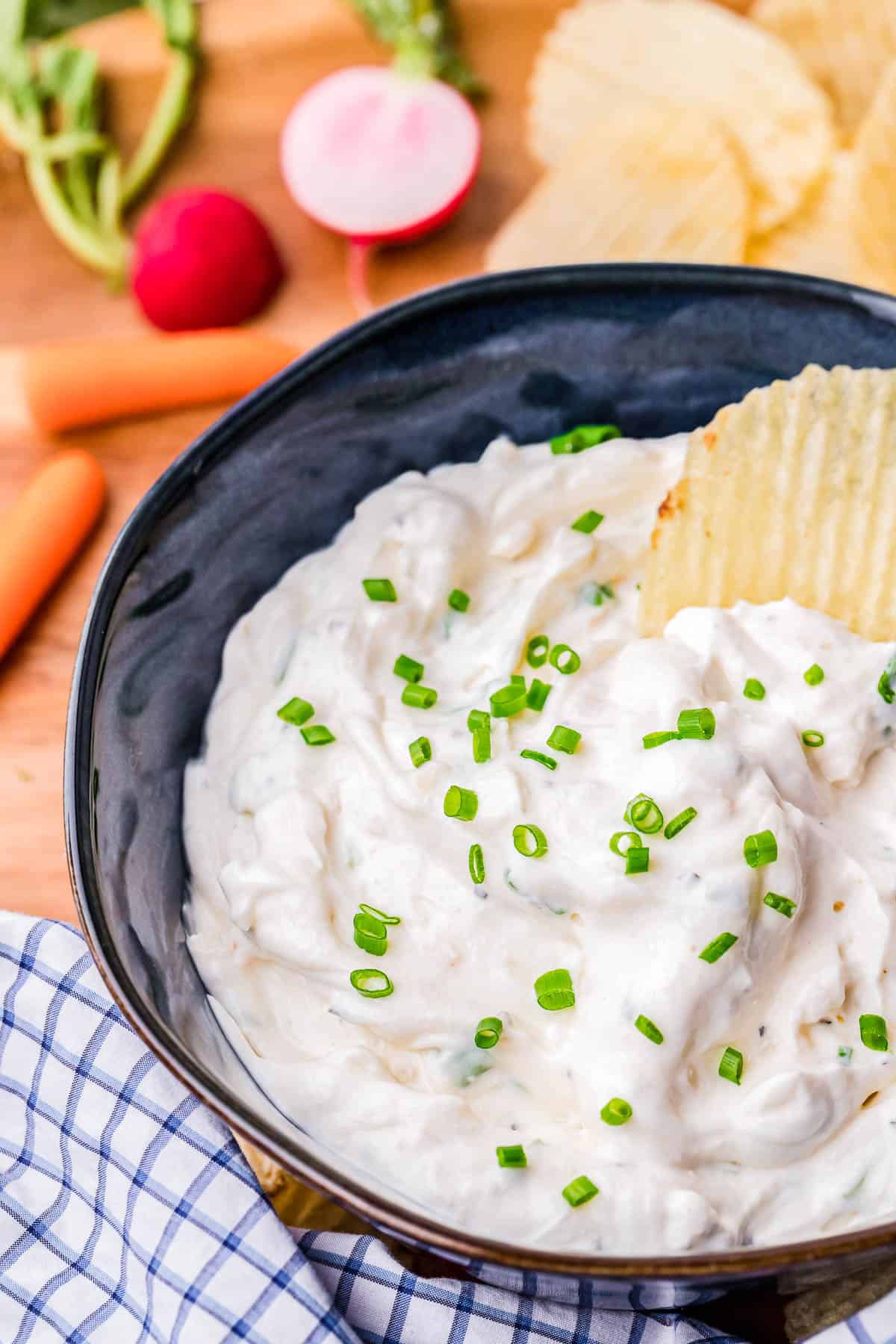 bowl of sour cream and onion dip with a chip in it
