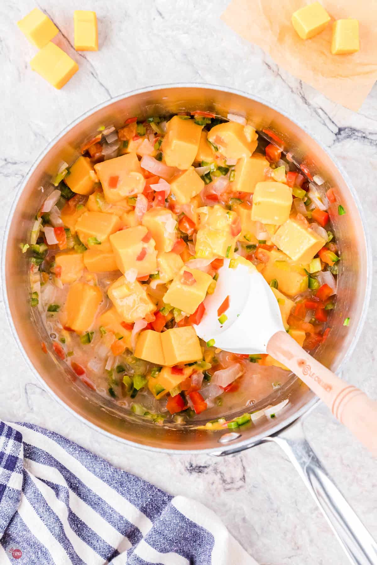 queso dip cooking in a pot with a white spatula