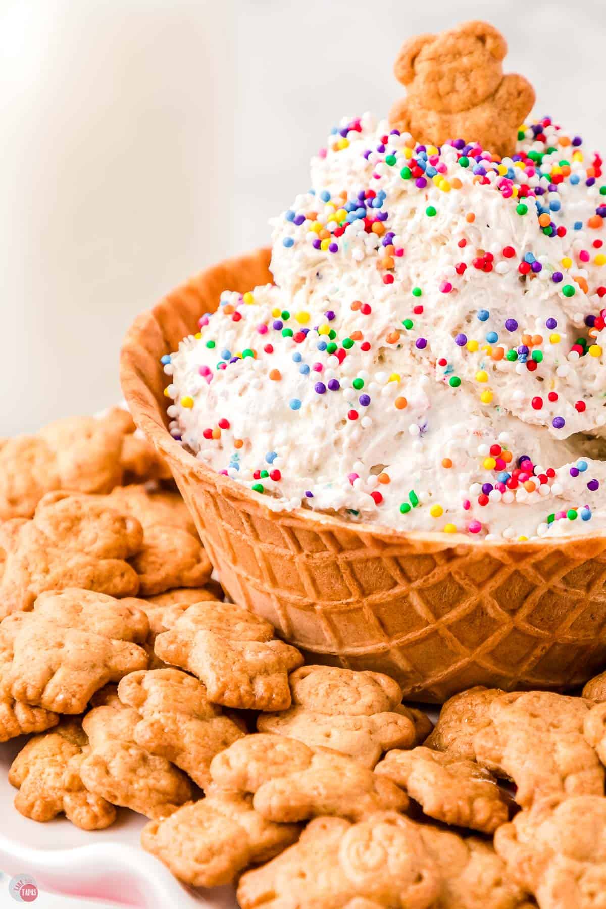 close up of waffle bowl full of funfetti dip with teddy grahams