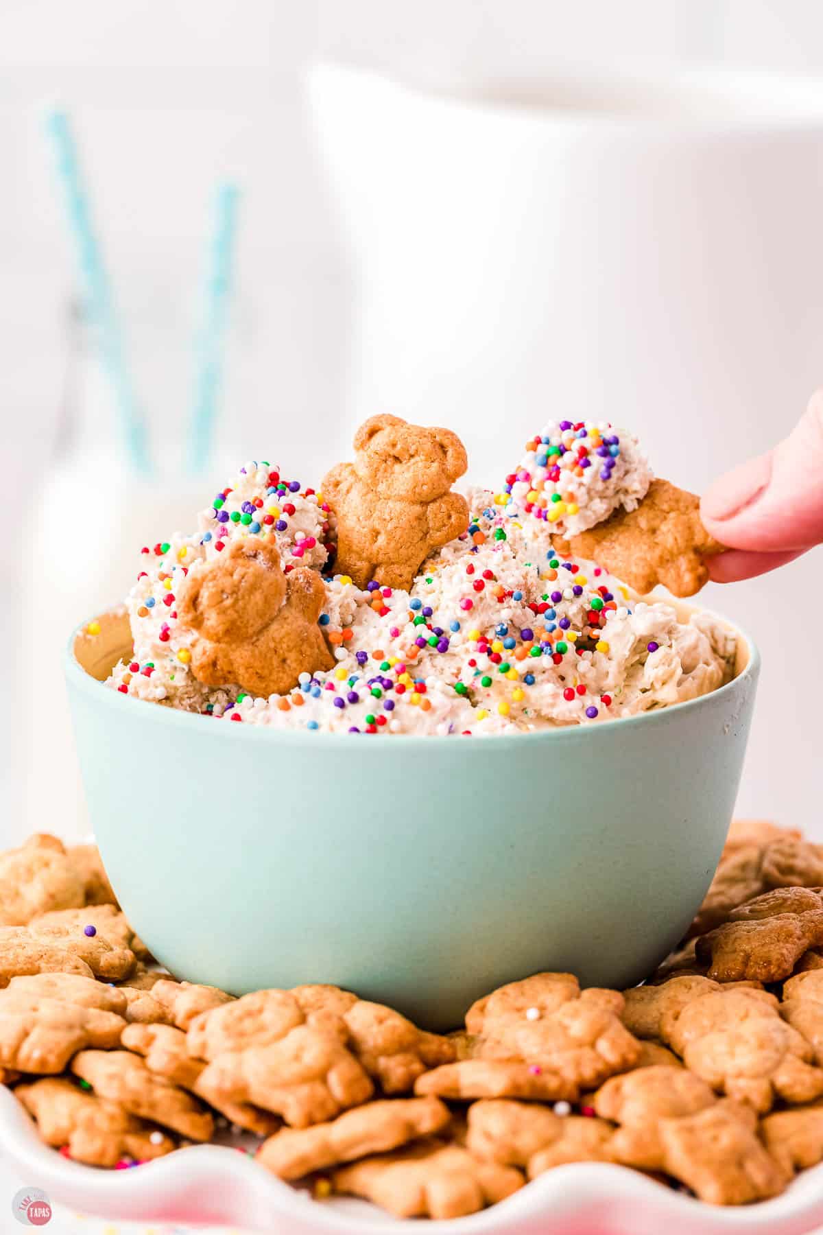 hand scooping cake mix dip out of a blue bowl