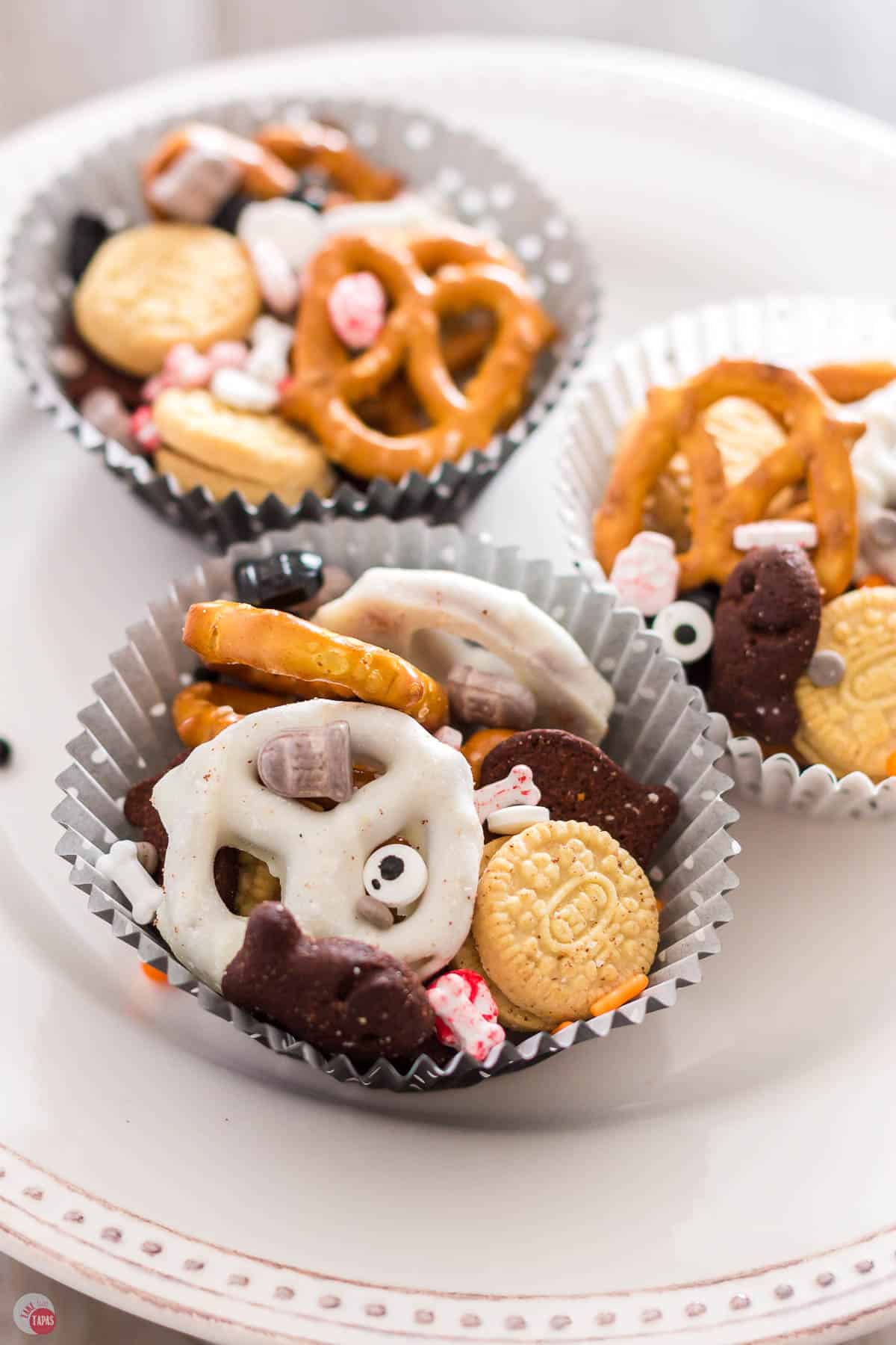 three cupcake liners with Halloween mix in them on a white cake plate