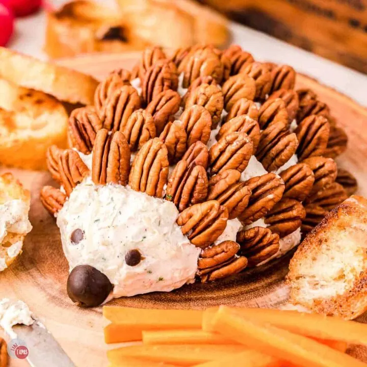 hedgehog cheese ball on a wood board with carrot sticks