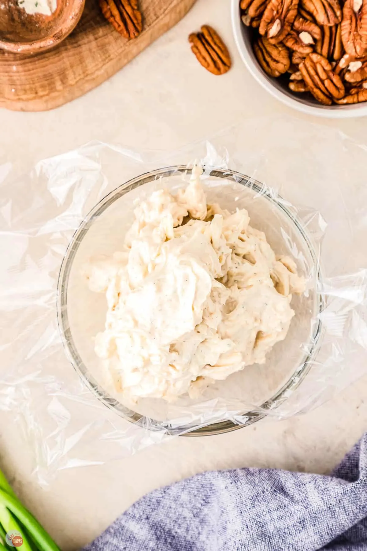 cream cheese mixture in a clear bowl on top of plastic wrap