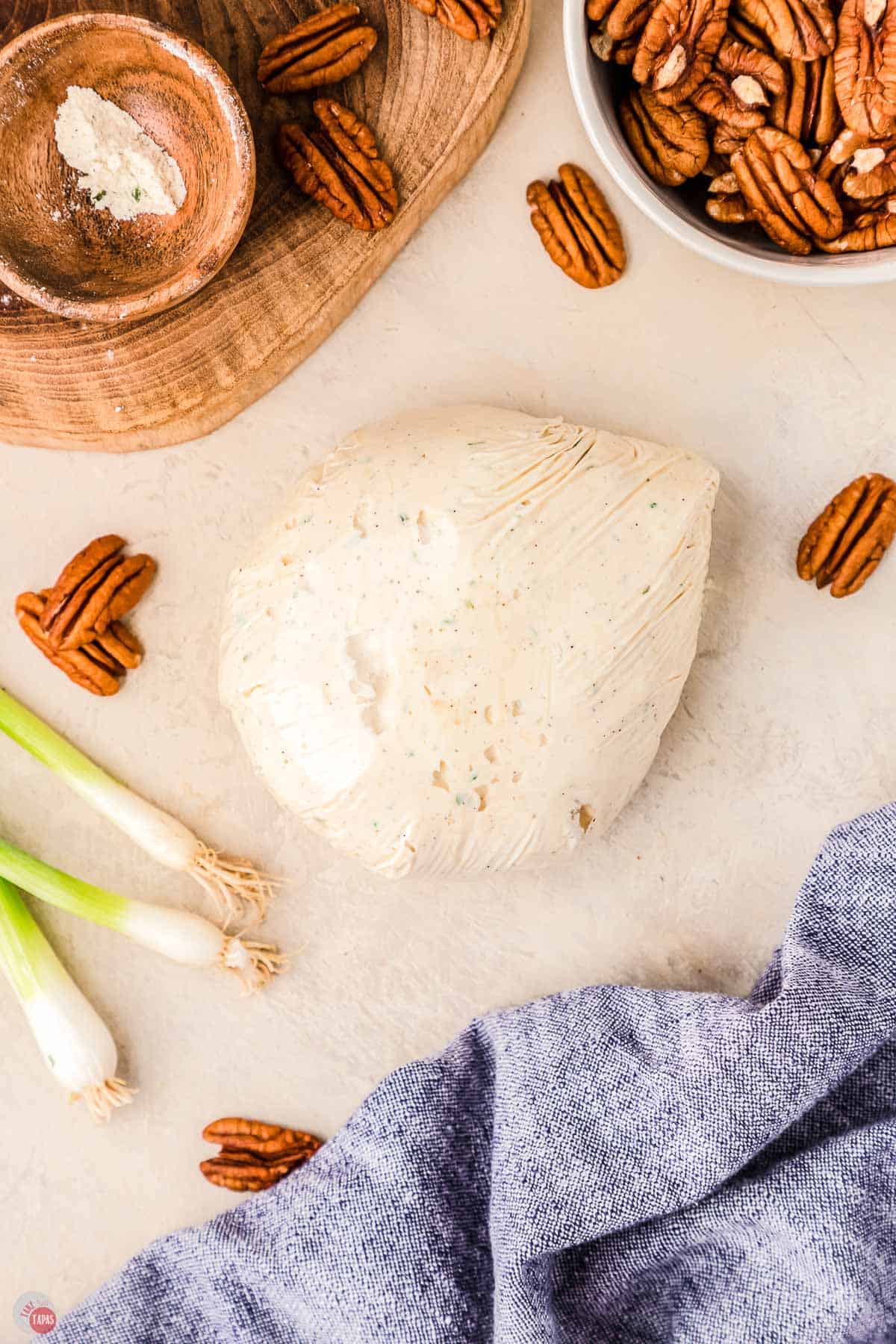 cone shaped cheese ball in plastic wrap with a blue napkin