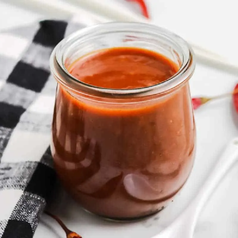 small jar of hoisin sauce with black and white napkin