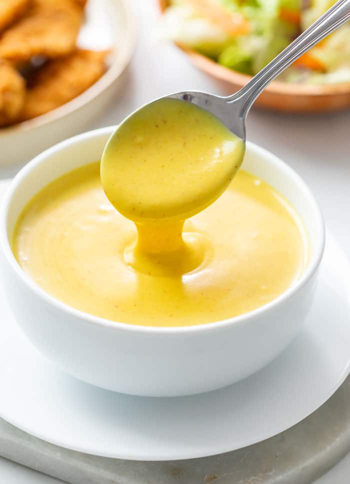 small white bowl of honey mustard with a spoon