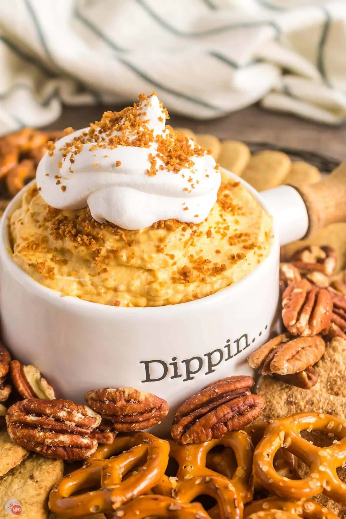 pumpkin dip in a white bowl surrounded by pretzels