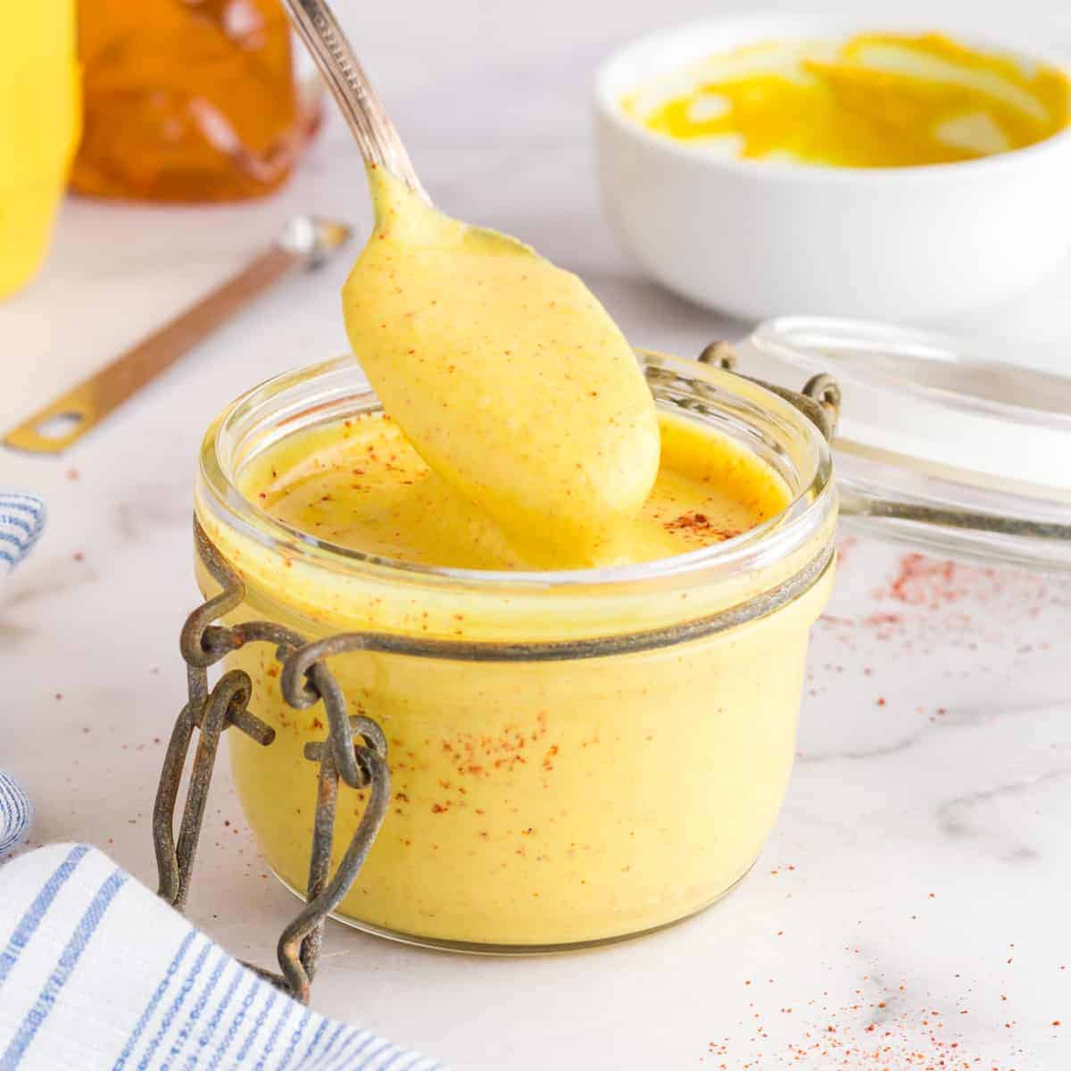 small clear jar of honey mustard with a spoon